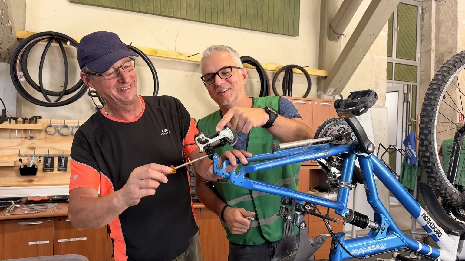 Deux mécanos bénévoles apprennent ensemble à réparer un vélo